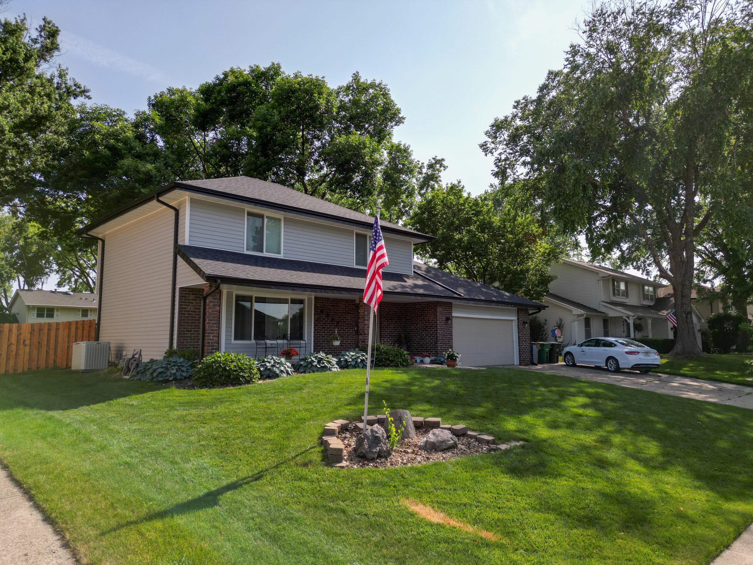 Angled view of a newly roofed two-story home with dark asphalt shingles.