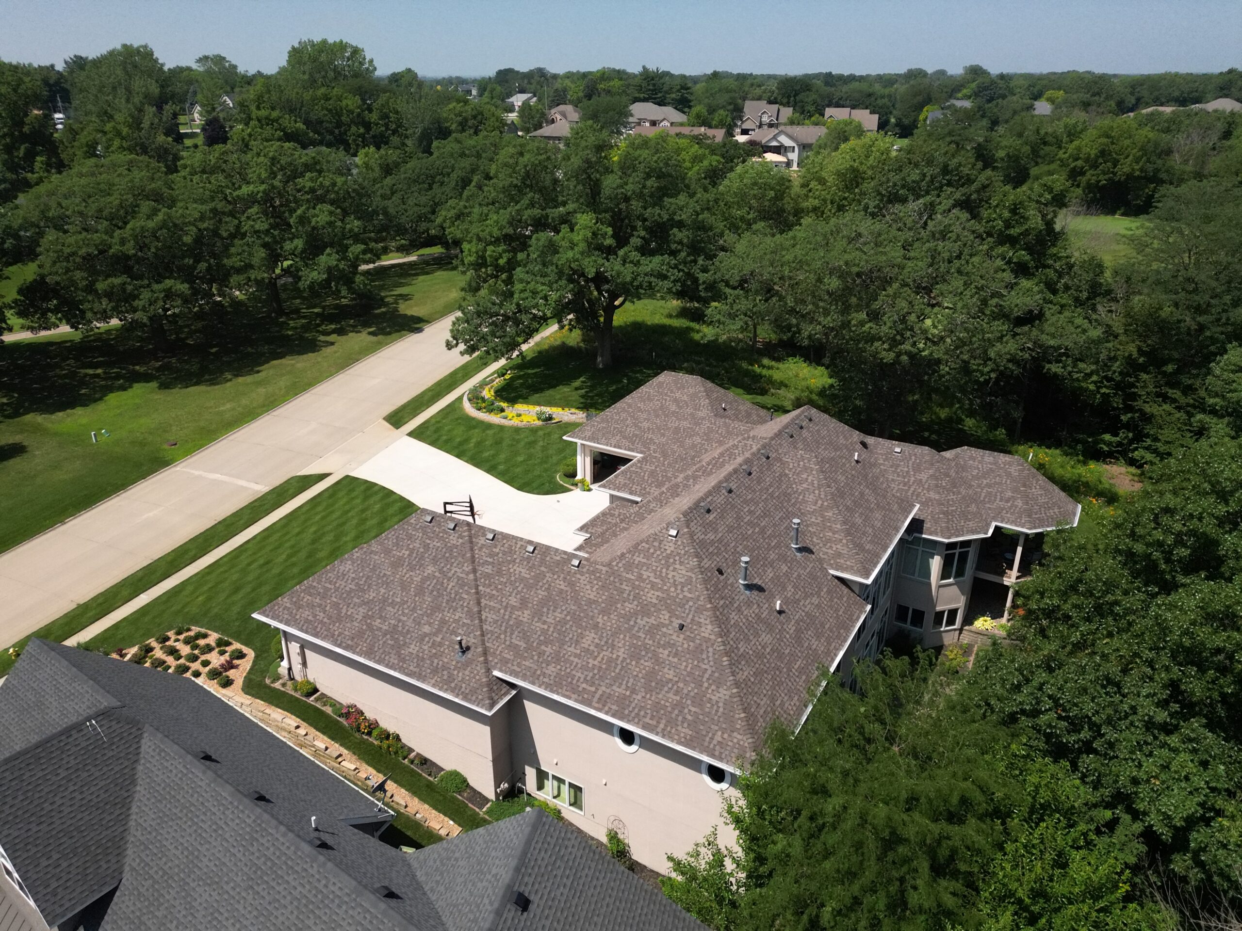 Aerial angled view from behind of a complex residential roof system installed by Wolf Roofing in Polk City