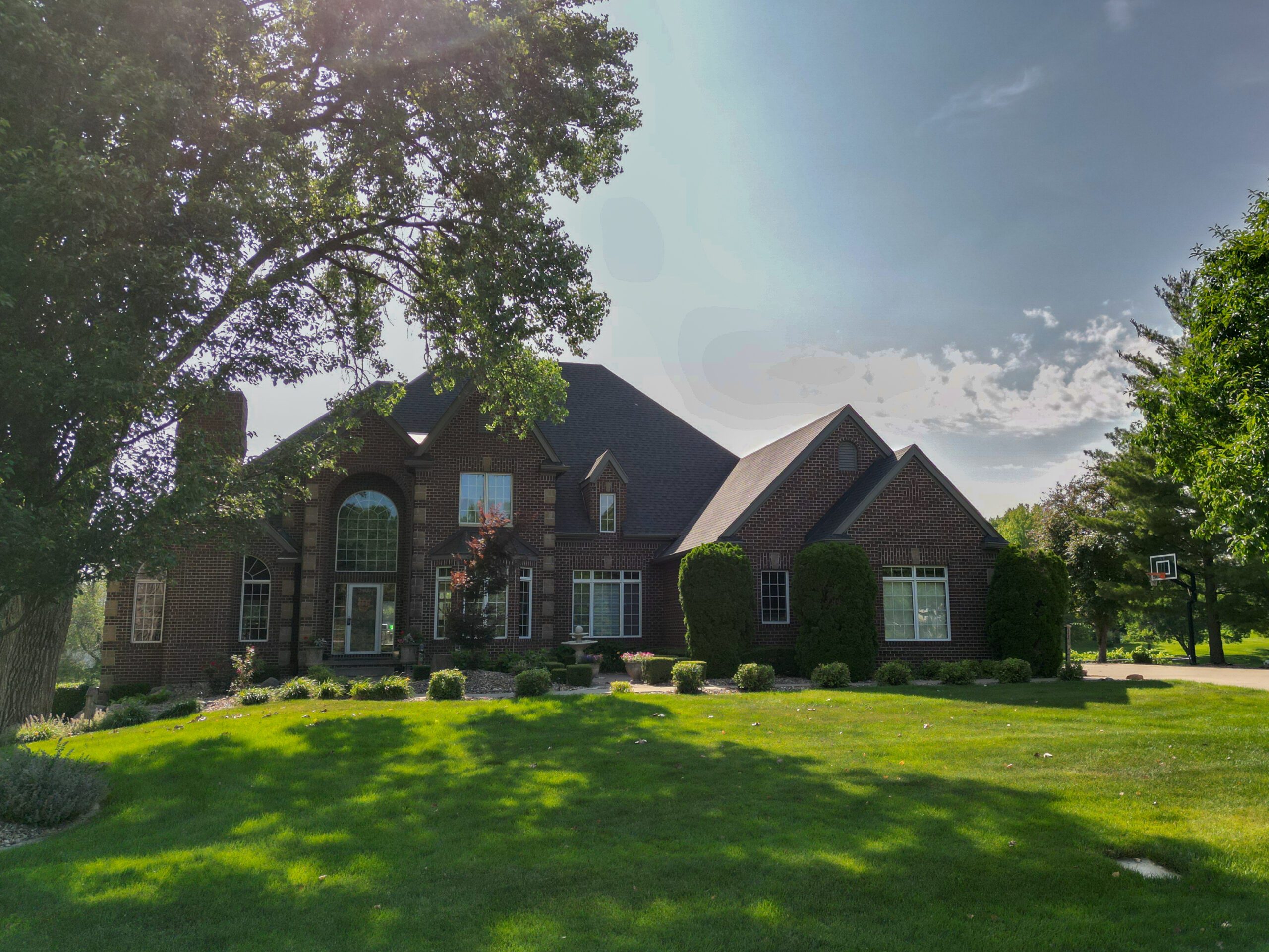 Large home in West Des Moines with new asphalt roofing, front view from below.
