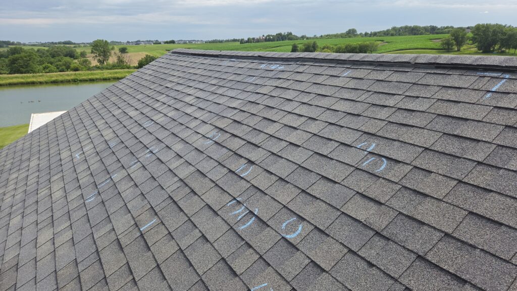 Chalk circles marking hail impacts on asphalt shingles during a Wolf Roofing inspection in Iowa
