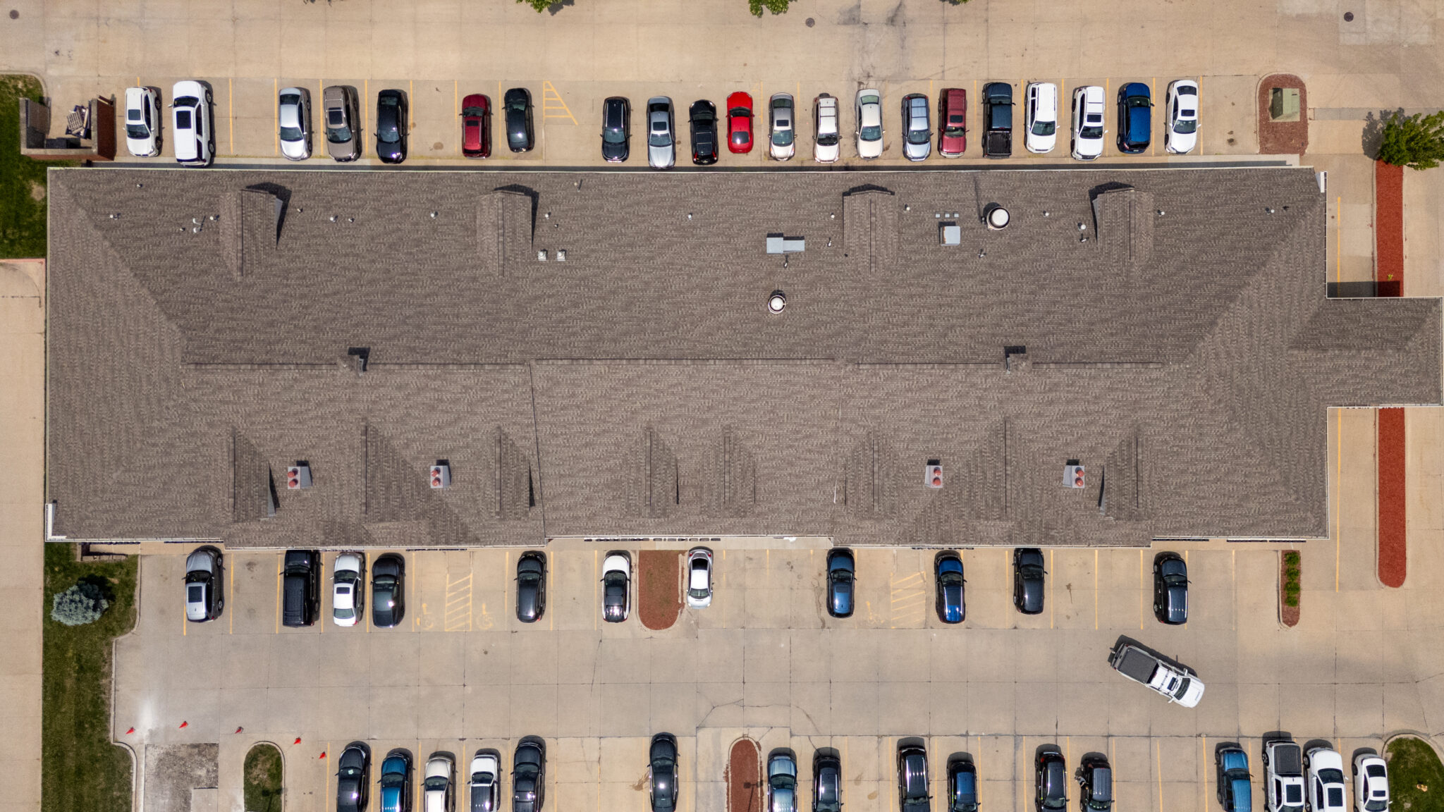 Aerial top-down view of a commercial building with a finished shingle roof and parking lot