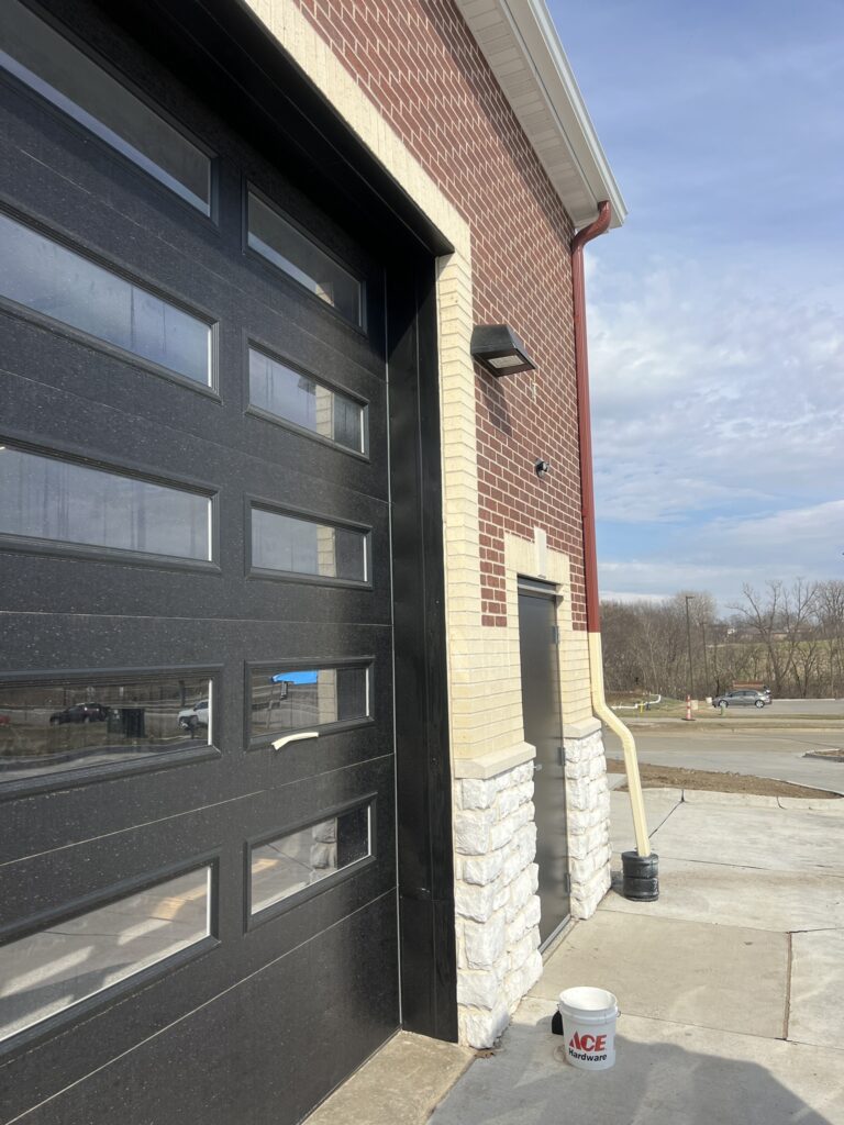 Seamless gutter and red downspout on a new brick commercial building with service bays