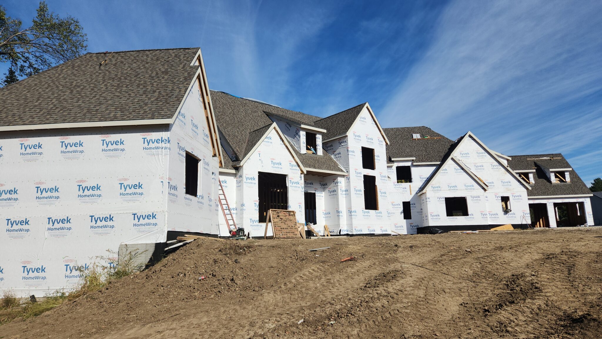 Large new build home wrapped in housewrap with the new shingle roof installed before siding