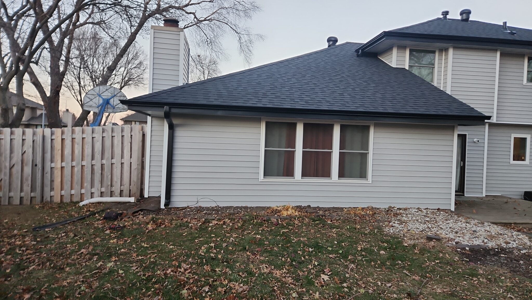 Home with a new dark shingle roof and matching seamless gutters installed together