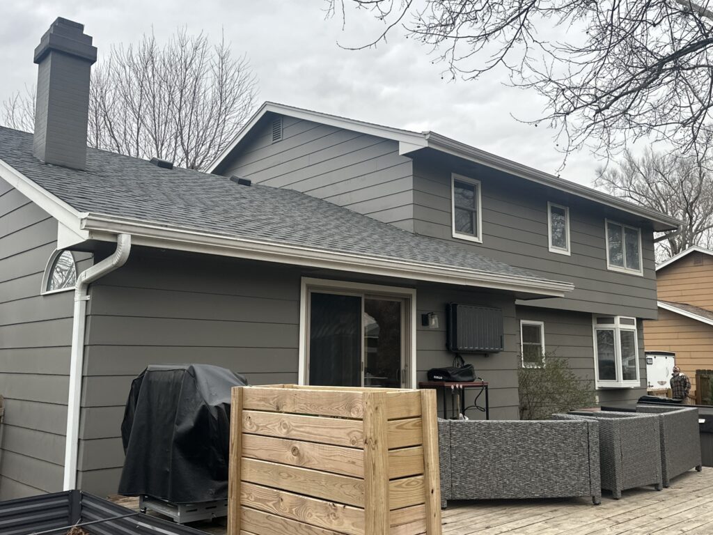 White seamless gutters and downspout on a gray two-story home with a patio