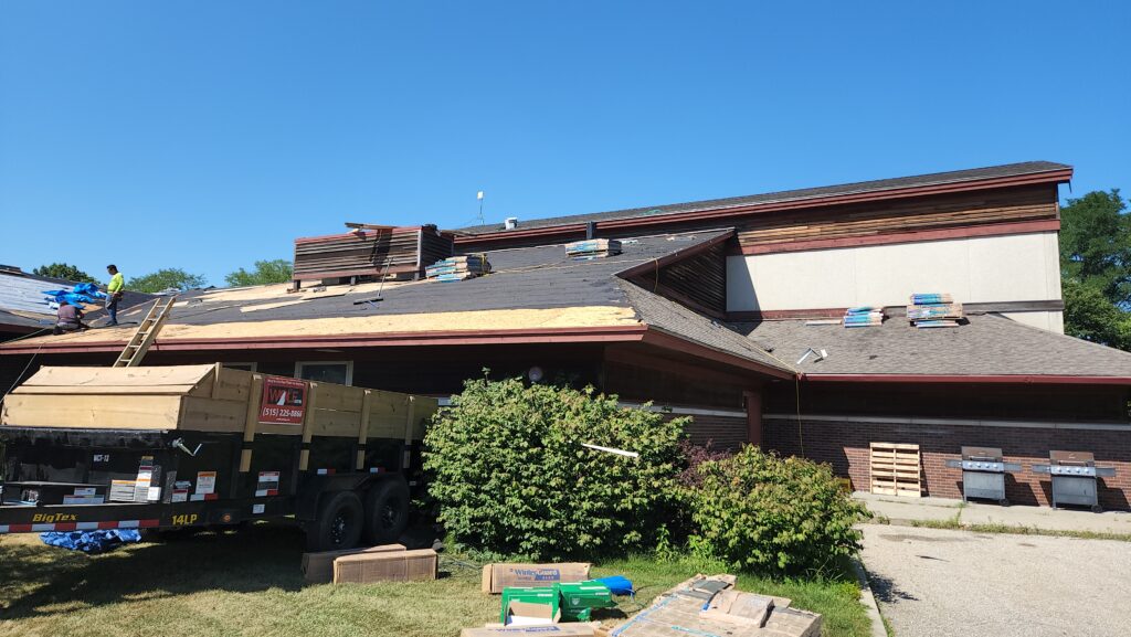 wolf-roofing-crew-commercial-roof-replacement-johnston-ia Wolf Roofing crew working on a commercial roof replacement in Johnston, IA