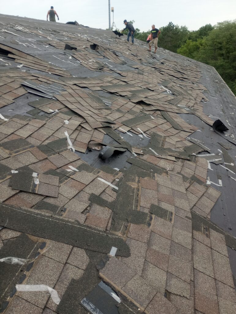 wolf-roofing-crew-shingle-tear-off-johnston-ia Wolf Roofing crew tearing off old shingles on a Johnston, IA community center