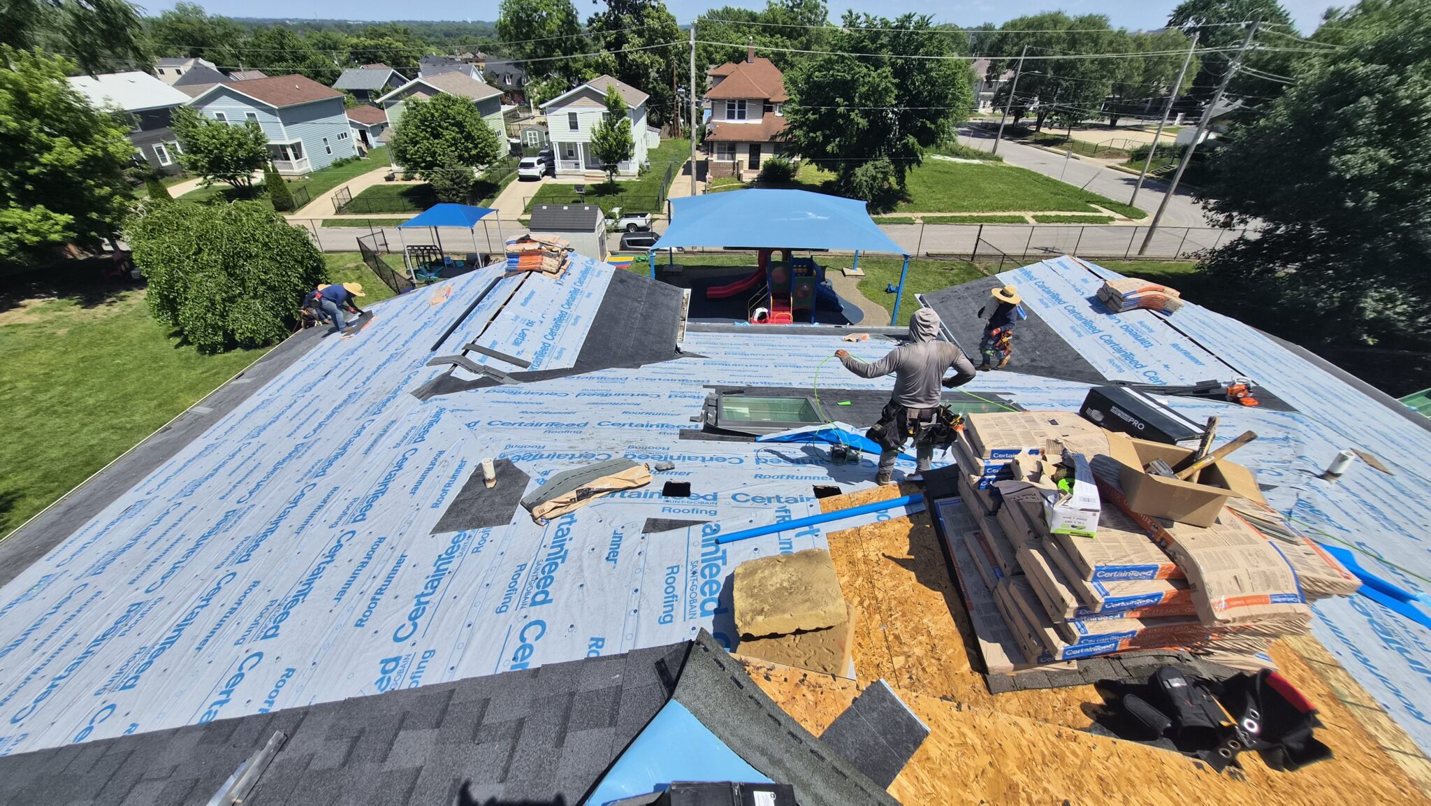 Wolf Roofing crew working on a large commercial roof with underlayment going down